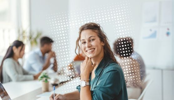 Lächelnde Person an Gruppentisch mit Stift in der Hand